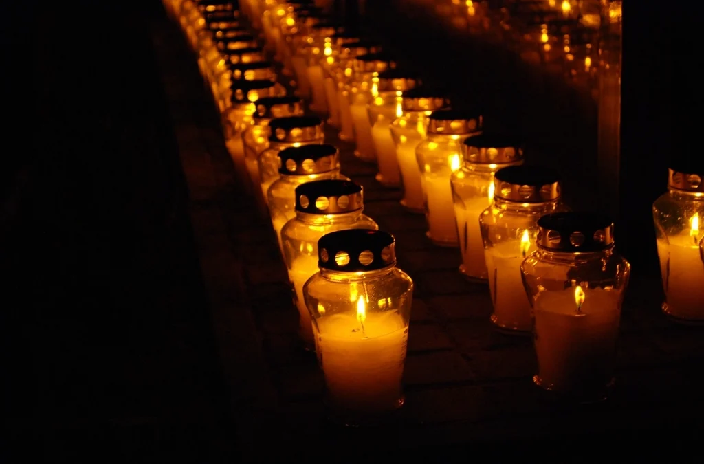 Lit candles and flowers on graves during All Saints' Day commemoration