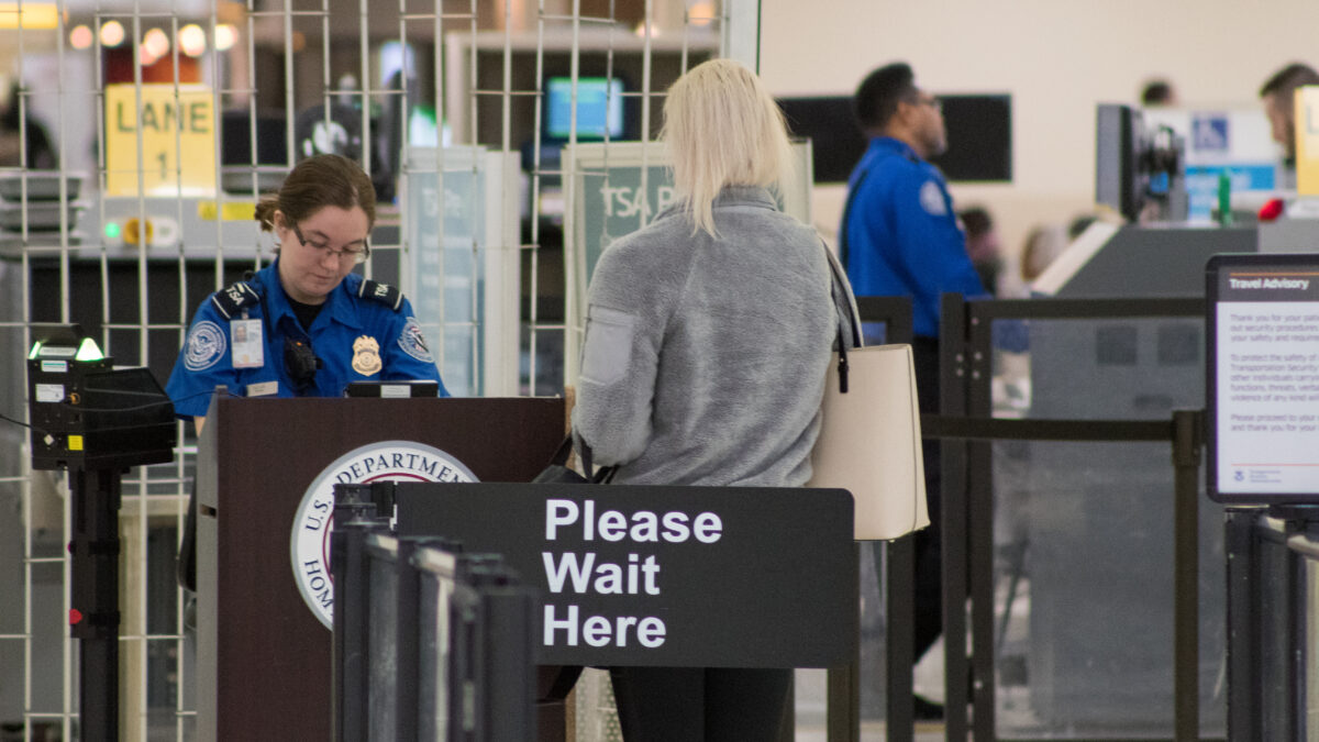Airport security screening area with passengers going through checkpoint