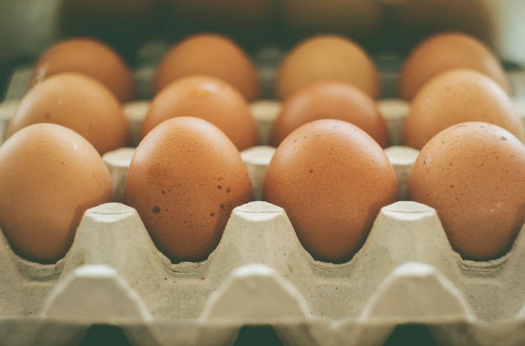 Brown eggs in a cardboard carton on a wooden table